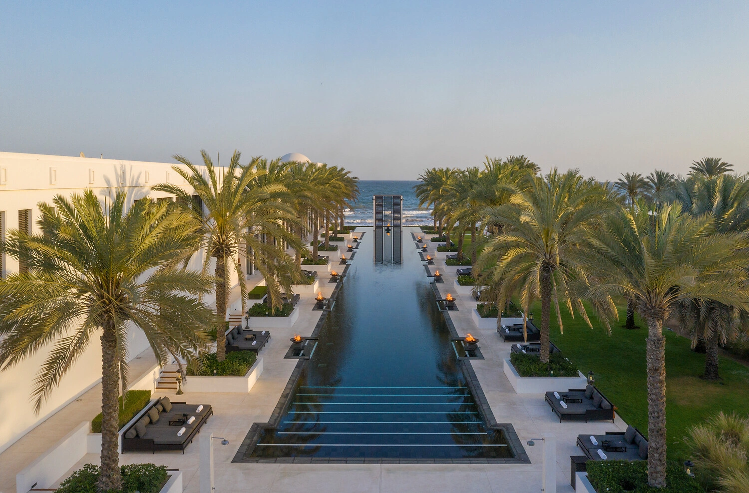 Der lange Pool des Luxusresorts Chedi Muscat mit palmengesäumtem Gehweg